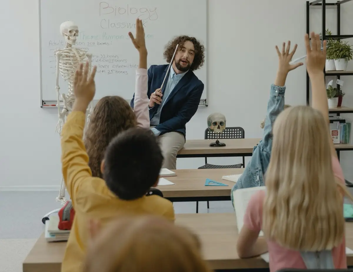 A teacher leading a lively lesson with pupils raising their hands