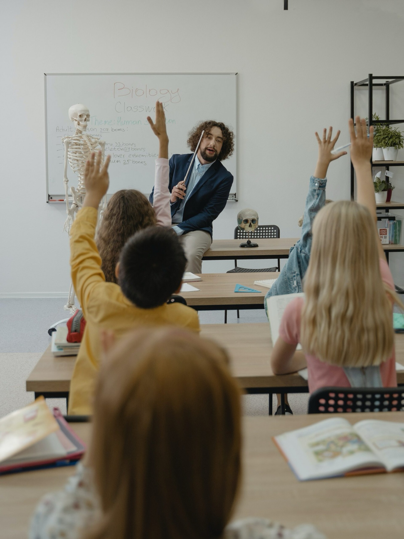 A teacher leading a lively lesson with pupils raising their hands