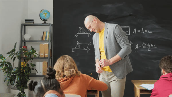 A teacher explaining a maths problem at the chalkboard