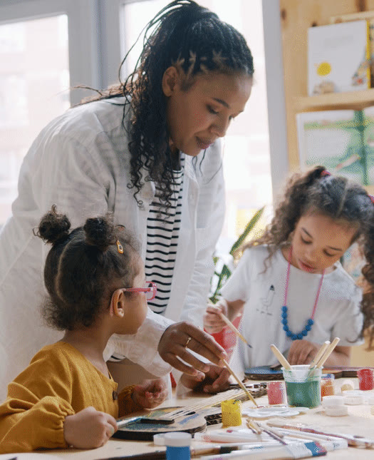 A teacher painting with two young pupils