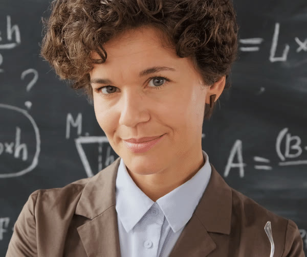 A teacher smiling in front of a chalkboard