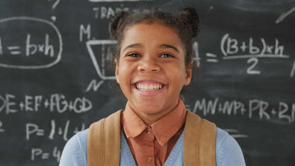 A smiling pupil in front of a chalkboard